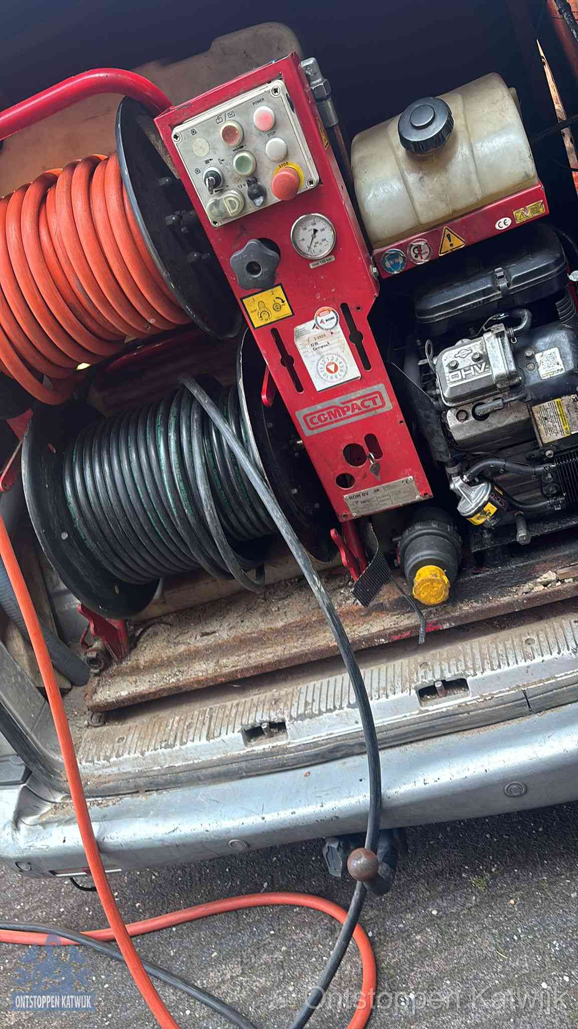 Een rood hogedruk-rioolreinigingstoestel met slangen in de laadbak van de bedrijfsbus, apparatuur voor een hardnekkige wc-verstopping in Katwijk
