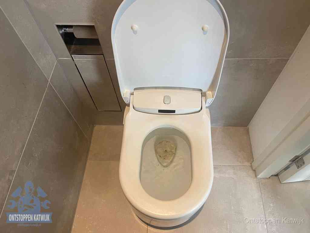 Een wit hangtoilet waarin een prop wc-papier op het water blijft drijven, een duidelijk signaal van een verstopte wc in Katwijk