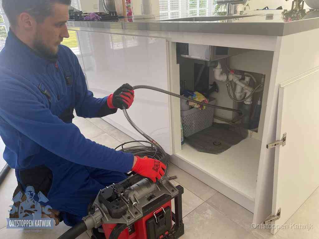 Een monteur reinigt de keukenafvoer grondig met een veermachine om terugkerende gootsteenverstoppingen te voorkomen in Katwijk