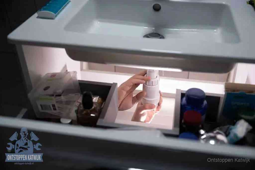 Een pompfles met zeep boven een wastafel in de toiletruimte, de warm water en afwasmiddel-methode om de wc te ontstoppen in Katwijk
