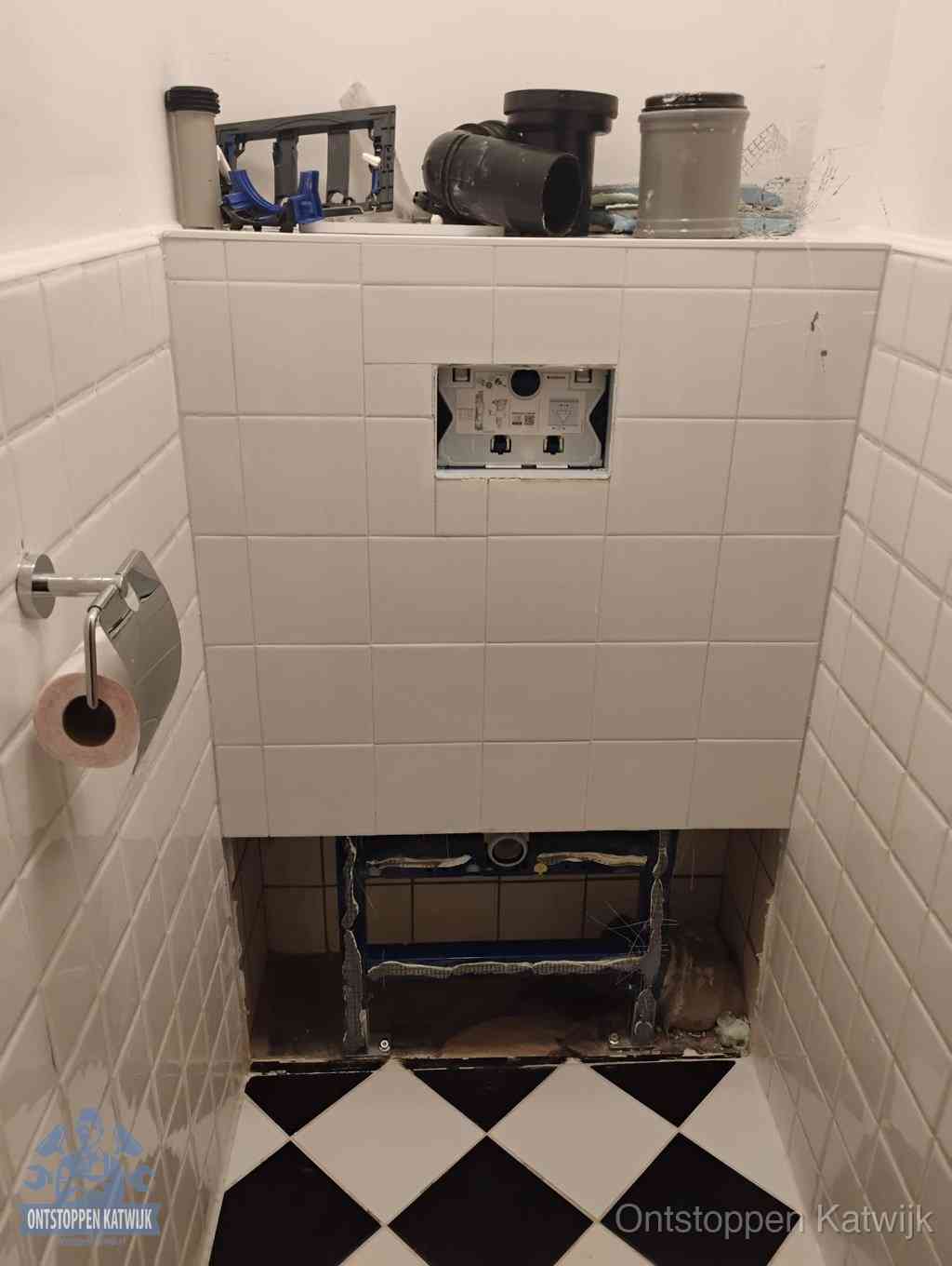 Een toiletruimte waar het hangtoilet en de inbouwreservoir-onderdelen zijn vrijgelegd voor onderhoud, periodiek nazicht voorkomt een wc-verstopping in Katwijk